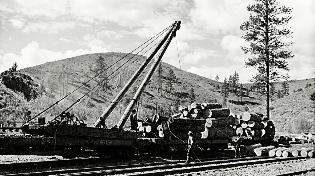 Digitally enhanced public domain photograph showing workers loading timber onto railcars using a crane during Arizona’s early railroad and logging expansion.