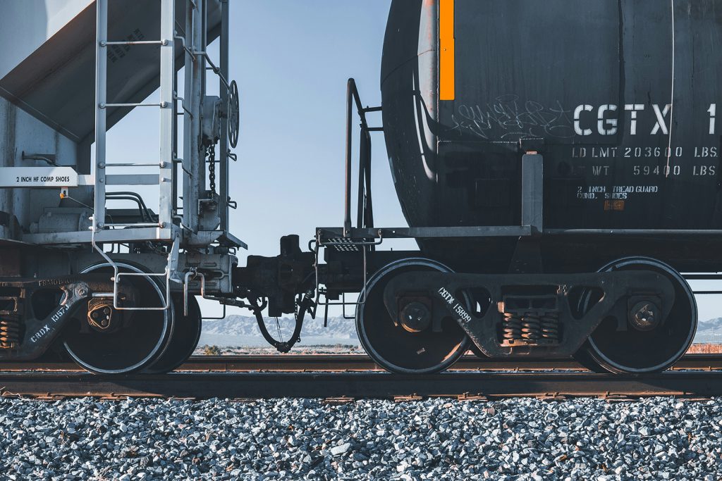 Close-up of coupled tank cars on the Apache Railway, desert mountains visible in the background.