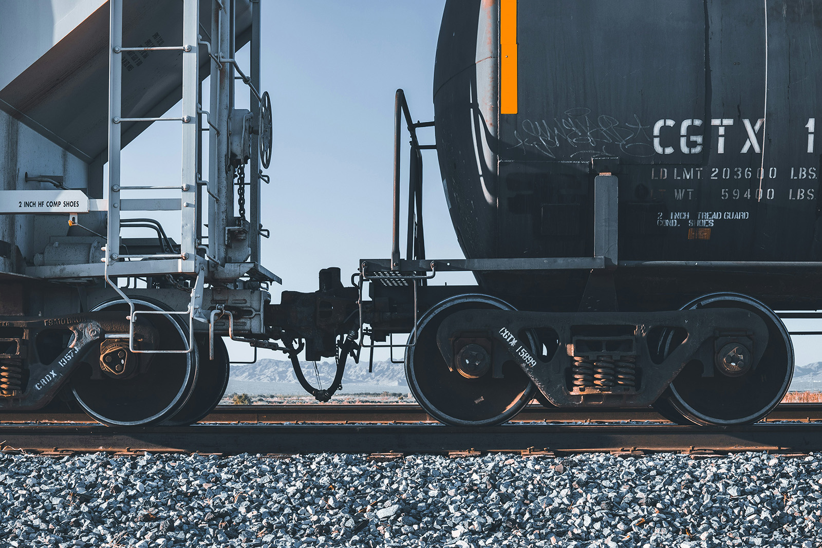 Close-up of coupled tank cars on the Apache Railway, desert mountains visible in the background.