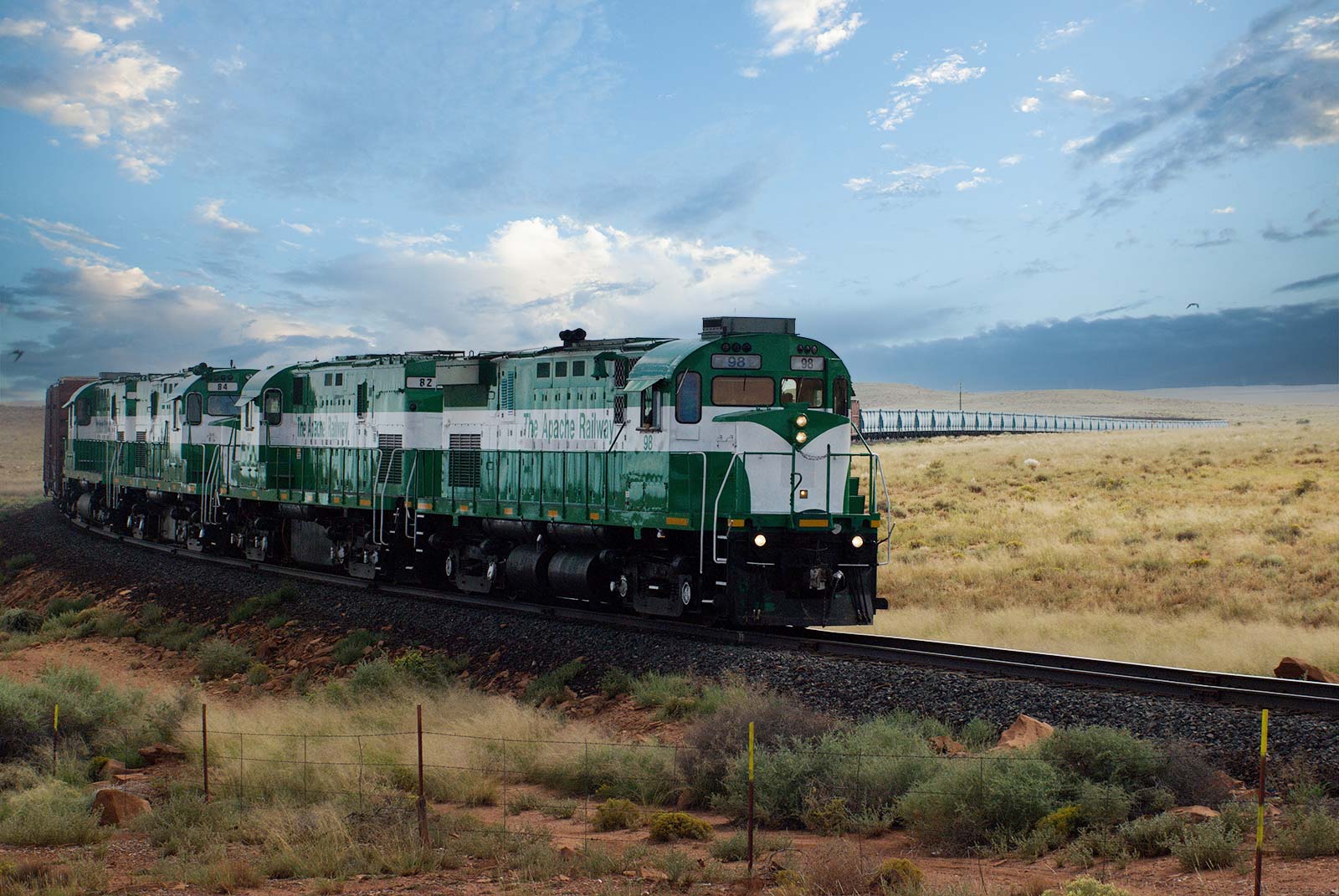 Apache Railway engines leading a freight train across Arizona grasslands, highlighting the role of short-line railroads in regional supply chains