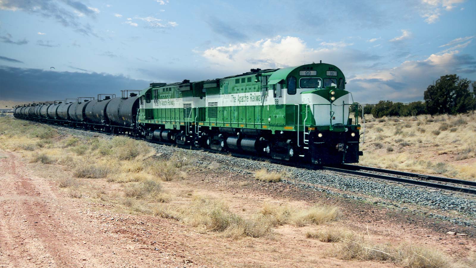 Apache Railway locomotive pulling tank cars through open desert terrain, representing short-line rail support for freight rail and industrial logistics