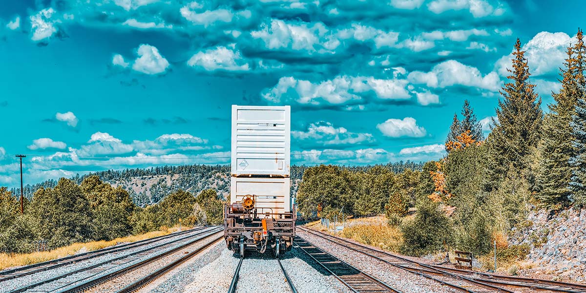 Railcar positioned on multiple tracks in a forested region, showing local rail infrastructure used by short-line and regional railroads