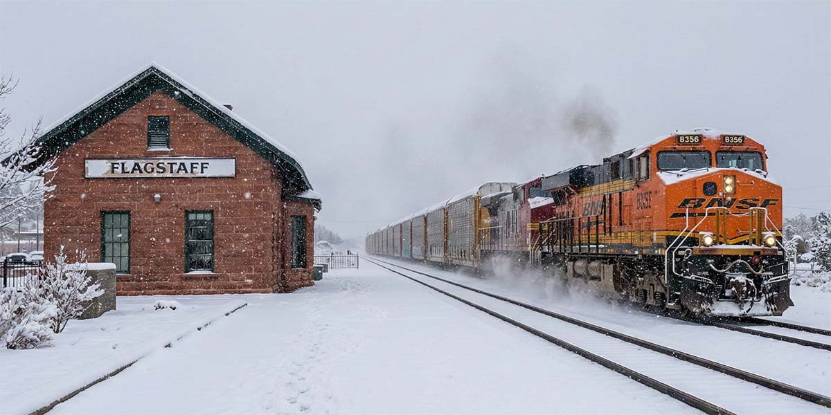 BNSF freight train passing the Flagstaff depot in winter, representing Class I rail connections that support regional short-line rail service